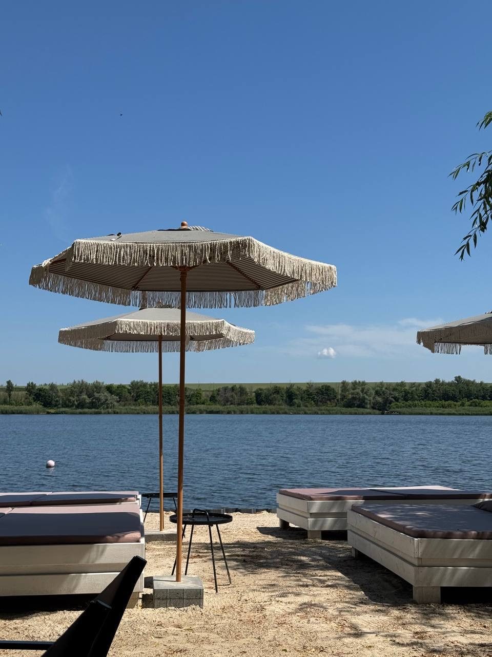 Парасолі з бахромою та лежаки на піску біля води